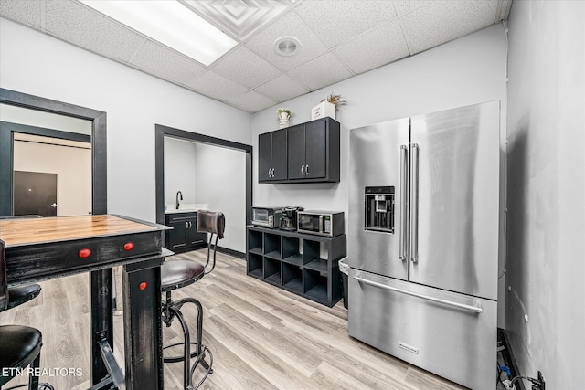 kitchen featuring stainless steel appliances, sink, light wood-type flooring, and a drop ceiling