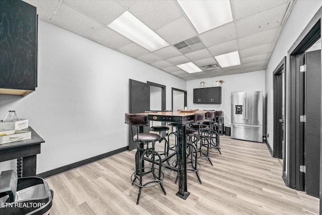 dining area featuring light wood-type flooring and a drop ceiling