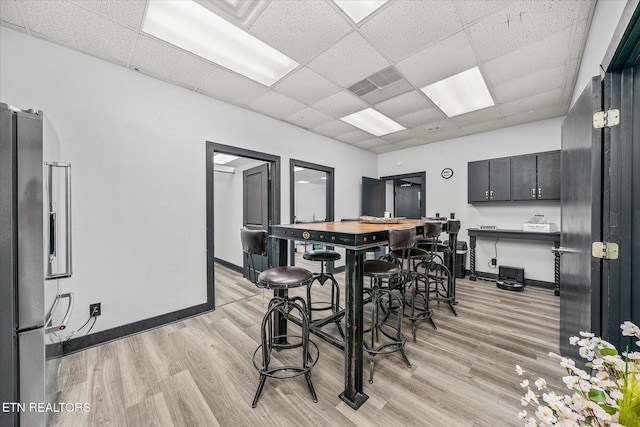 dining room featuring a drop ceiling and light hardwood / wood-style flooring