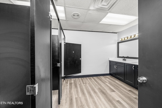 bathroom with hardwood / wood-style flooring, vanity, and a drop ceiling