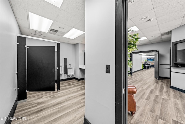 corridor featuring a paneled ceiling and light wood-type flooring