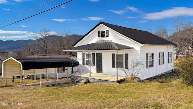 rear view of house featuring a carport, a yard, and a mountain view