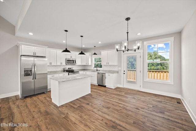 kitchen featuring white cabinetry, a center island, appliances with stainless steel finishes, pendant lighting, and light stone countertops