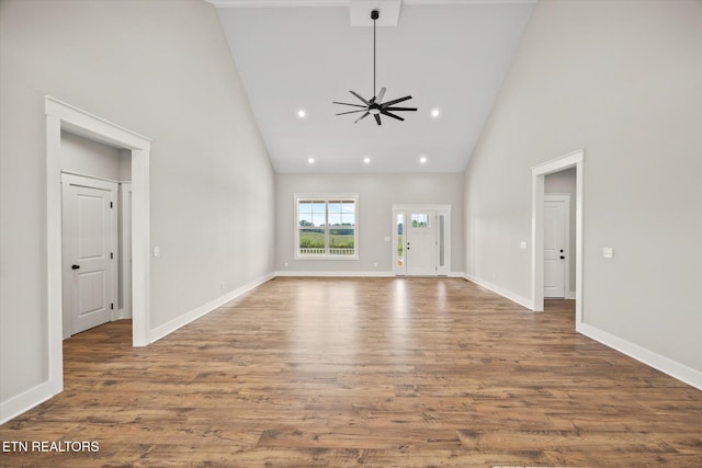 unfurnished living room with ceiling fan, hardwood / wood-style floors, and high vaulted ceiling