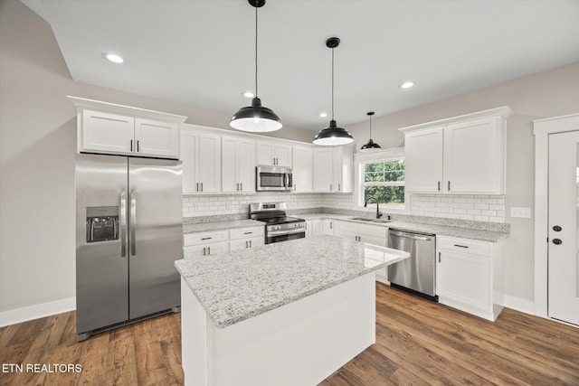 kitchen featuring white cabinetry, stainless steel appliances, sink, and a kitchen island