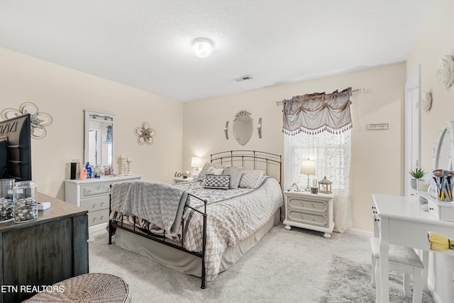 bedroom with light colored carpet and a textured ceiling