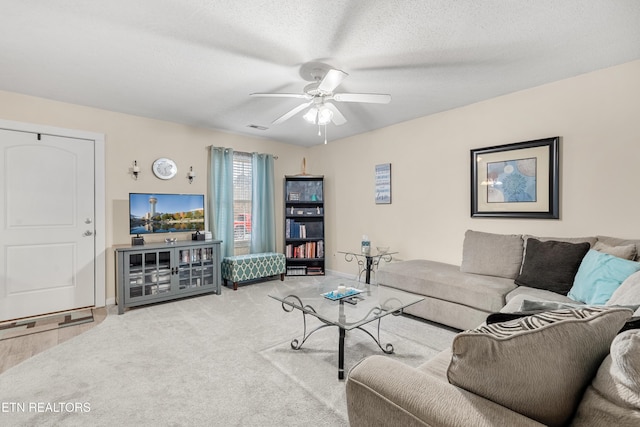 carpeted living room with ceiling fan and a textured ceiling