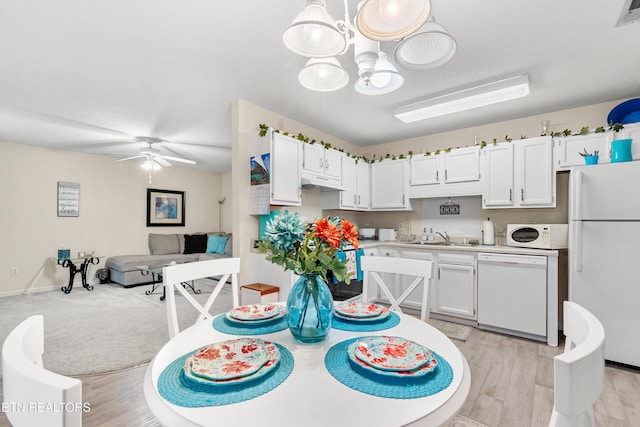 dining space featuring sink, ceiling fan with notable chandelier, and light hardwood / wood-style flooring