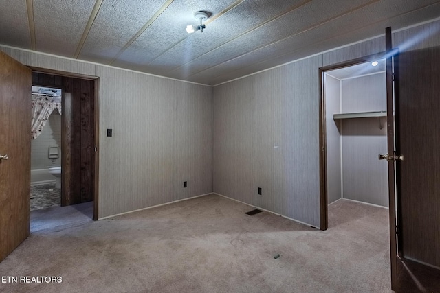 interior space with light carpet, a closet, and wood walls