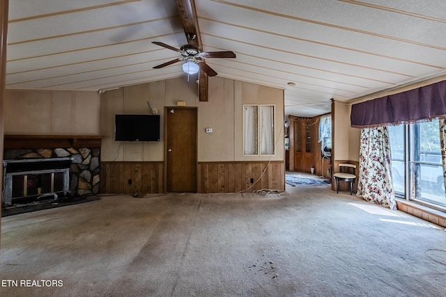 unfurnished living room with a stone fireplace, lofted ceiling with beams, ceiling fan, and carpet flooring