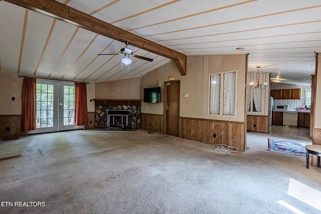 unfurnished living room featuring carpet floors, a stone fireplace, vaulted ceiling with beams, and ceiling fan