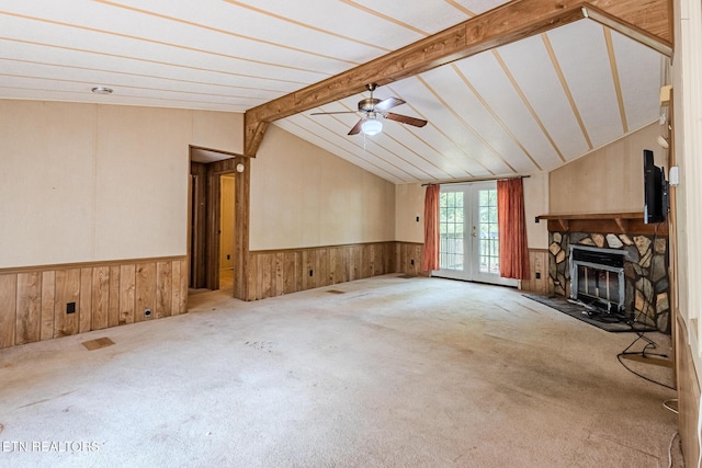 unfurnished living room with french doors, lofted ceiling with beams, ceiling fan, a fireplace, and carpet