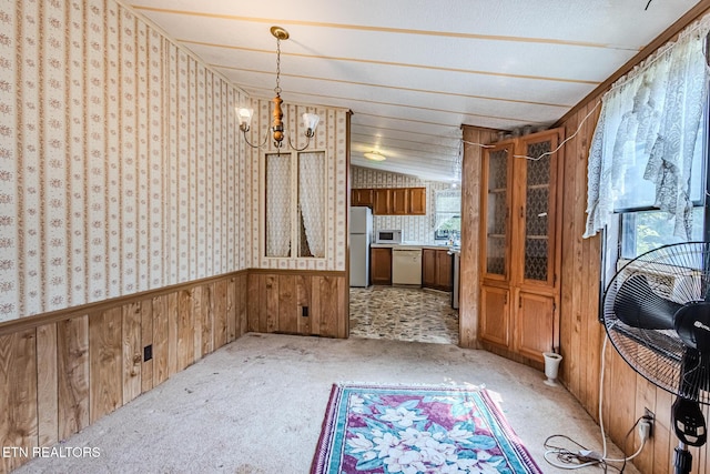 interior space featuring a notable chandelier, white appliances, wooden walls, and light colored carpet