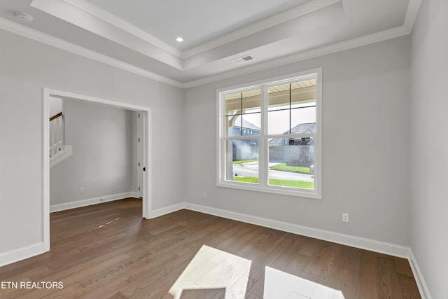 spare room featuring ornamental molding, a tray ceiling, and hardwood / wood-style floors