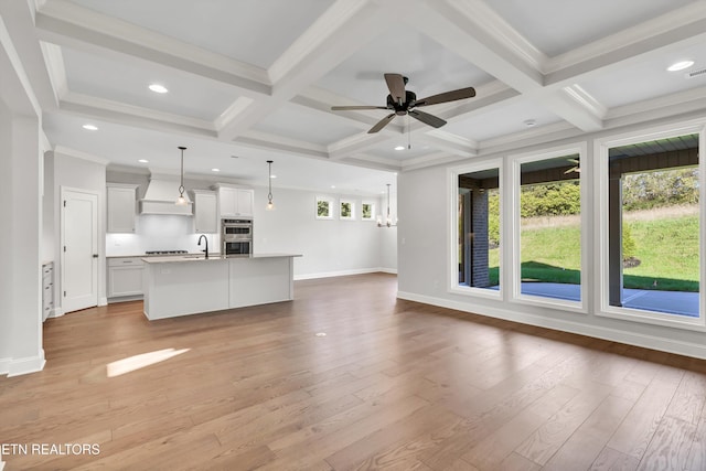 unfurnished living room featuring coffered ceiling, beam ceiling, and light wood-type flooring