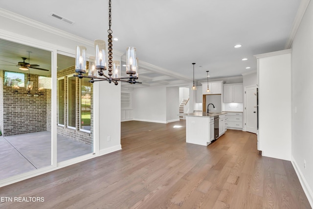 kitchen featuring white cabinetry, hanging light fixtures, ornamental molding, a kitchen island with sink, and light hardwood / wood-style flooring