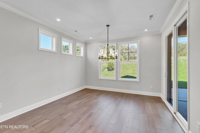 unfurnished dining area with an inviting chandelier, ornamental molding, a healthy amount of sunlight, and wood-type flooring