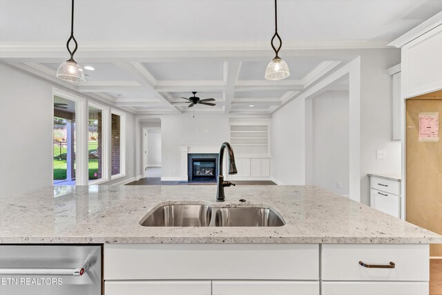 kitchen featuring beamed ceiling, coffered ceiling, sink, and decorative light fixtures