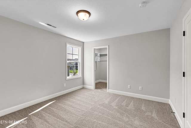 unfurnished bedroom featuring a closet, a spacious closet, and carpet