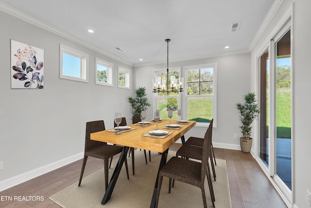 dining room with crown molding, hardwood / wood-style floors, and a notable chandelier