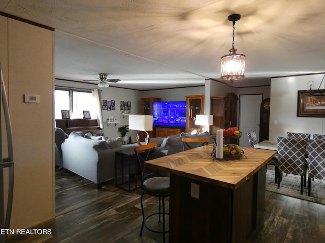 kitchen with dark hardwood / wood-style flooring, pendant lighting, butcher block counters, and a kitchen bar