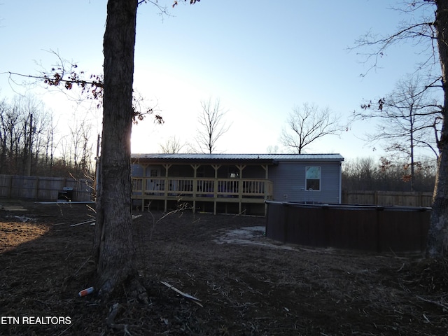 back of house featuring a wooden deck and a jacuzzi