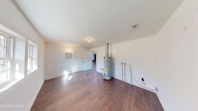 empty room with dark hardwood / wood-style floors and water heater