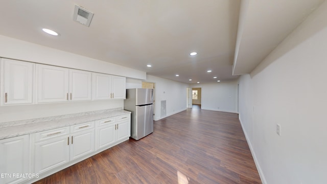 kitchen featuring white cabinetry, light stone counters, stainless steel fridge, and dark wood-type flooring