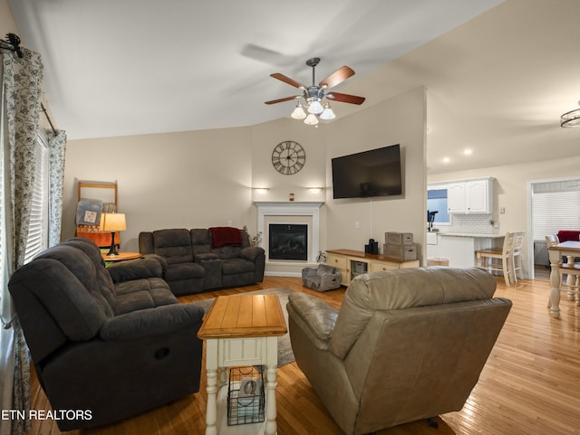 living room with ceiling fan, lofted ceiling, and light hardwood / wood-style floors