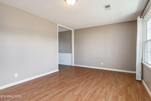 spare room with a healthy amount of sunlight, hardwood / wood-style floors, and a textured ceiling