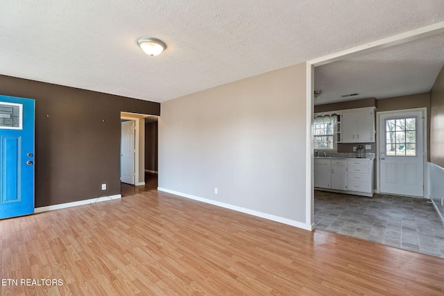 spare room with light wood-type flooring and a textured ceiling