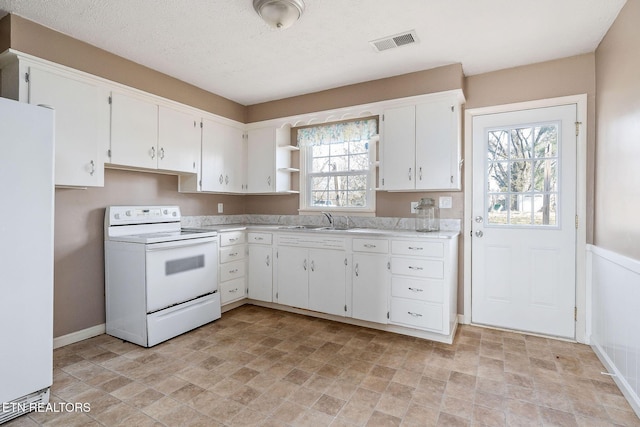 kitchen with white appliances, a wealth of natural light, sink, and white cabinets