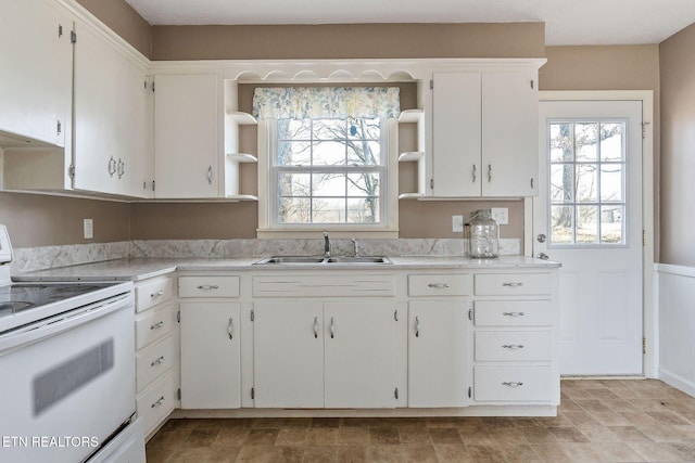 kitchen with white cabinetry, white electric range, sink, and a wealth of natural light