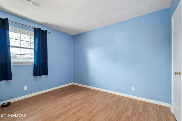 spare room featuring a textured ceiling and light hardwood / wood-style flooring