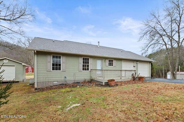 rear view of property with a shed, a garage, a yard, and a wooden deck