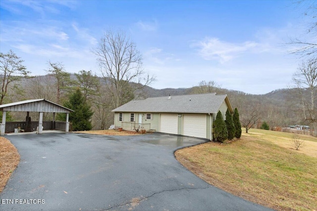 single story home featuring a mountain view, a garage, a front lawn, and a carport