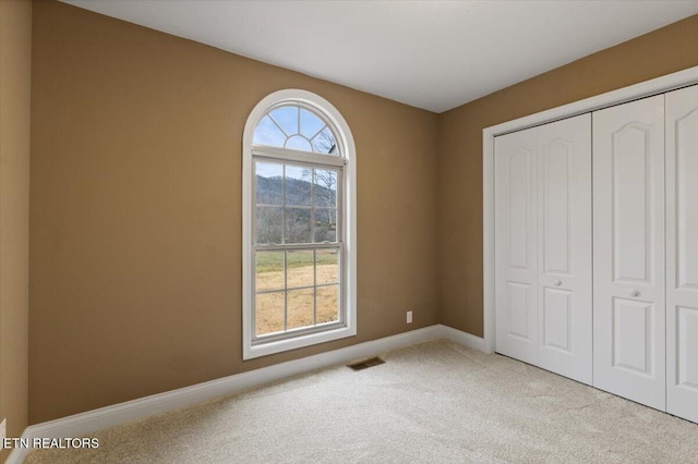 unfurnished bedroom featuring light colored carpet and a closet