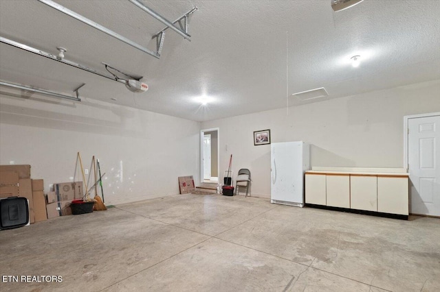 garage featuring a garage door opener and white fridge