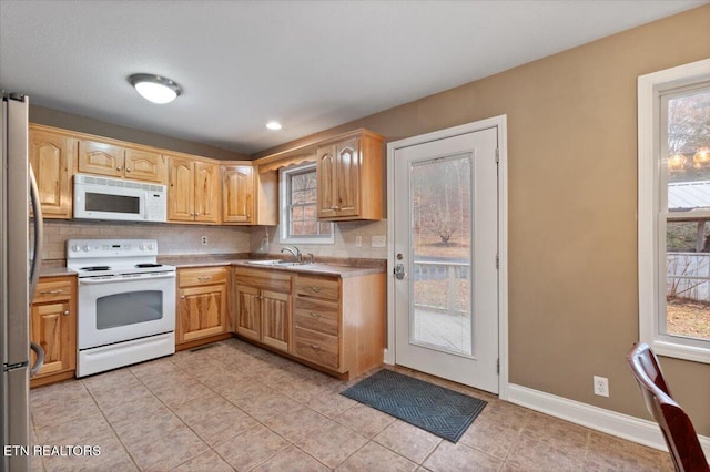 kitchen featuring tasteful backsplash, white appliances, plenty of natural light, and sink