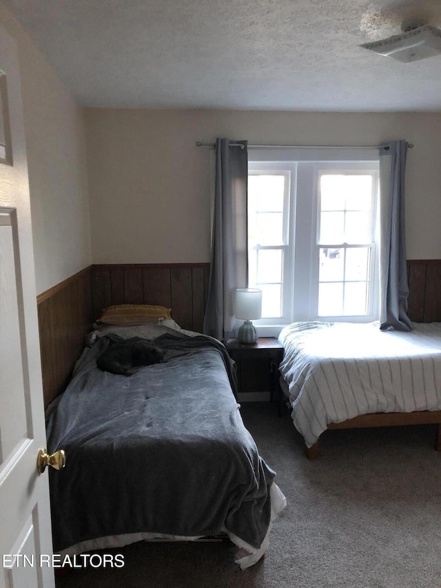 bedroom featuring carpet floors, a textured ceiling, and wood walls