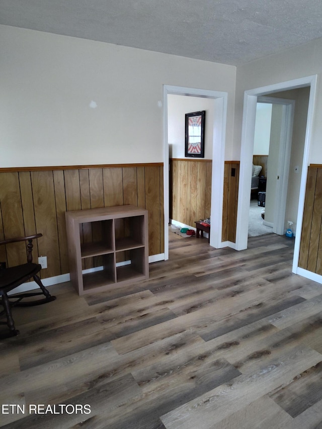 interior space with wooden walls, dark hardwood / wood-style floors, and a textured ceiling