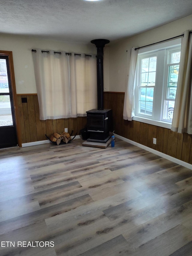 living room featuring wooden walls, wood-type flooring, and a wood stove