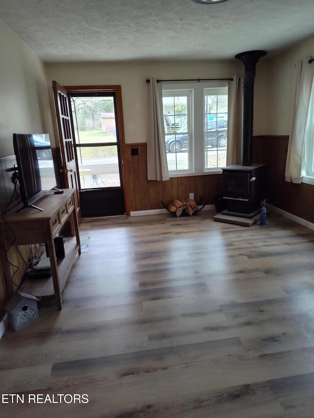 interior space featuring a wood stove, light hardwood / wood-style floors, a textured ceiling, and a wealth of natural light