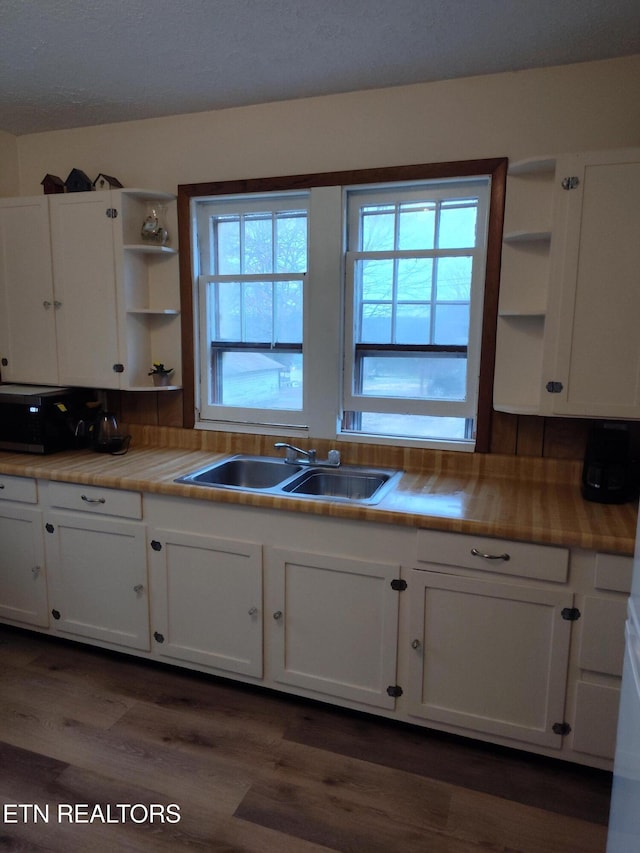 kitchen with a healthy amount of sunlight, dark hardwood / wood-style floors, sink, and white cabinets