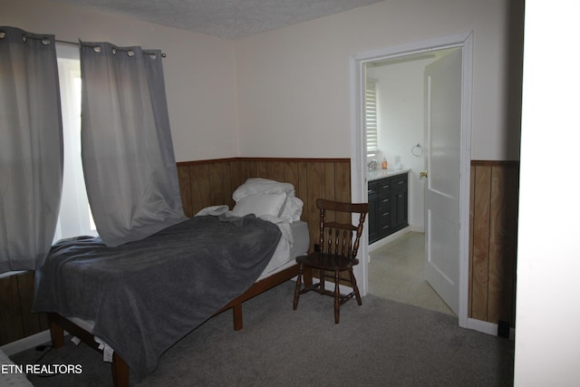 bedroom with a wainscoted wall, wood walls, and a textured ceiling