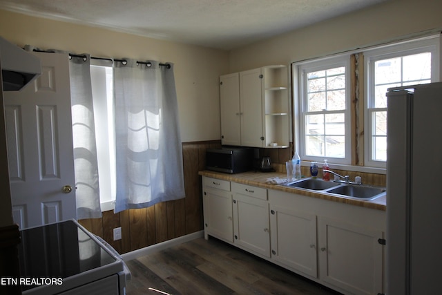 kitchen featuring freestanding refrigerator, white cabinets, stainless steel microwave, and a sink