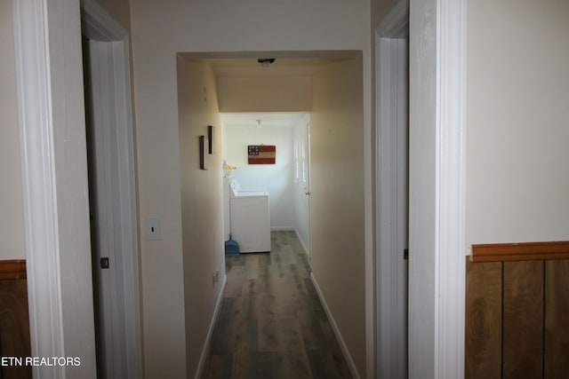 hallway with dark wood-type flooring, washer / clothes dryer, and baseboards