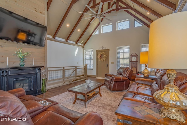 living room featuring beamed ceiling, a towering ceiling, ceiling fan, and light hardwood / wood-style flooring