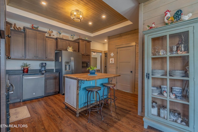 kitchen featuring appliances with stainless steel finishes, butcher block counters, a center island, a tray ceiling, and wooden ceiling