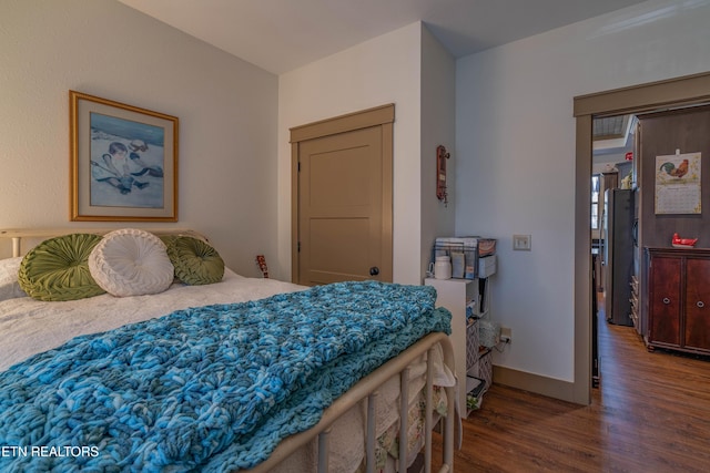 bedroom featuring dark wood-type flooring and stainless steel refrigerator